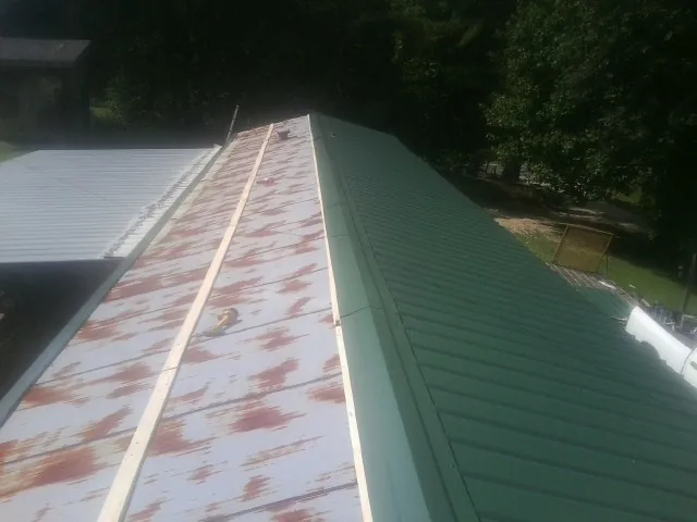 Old rusted panels beside newly installed green metal roofing — Wind Damage Roof Repair by Roofing Brothers in Duncanville
